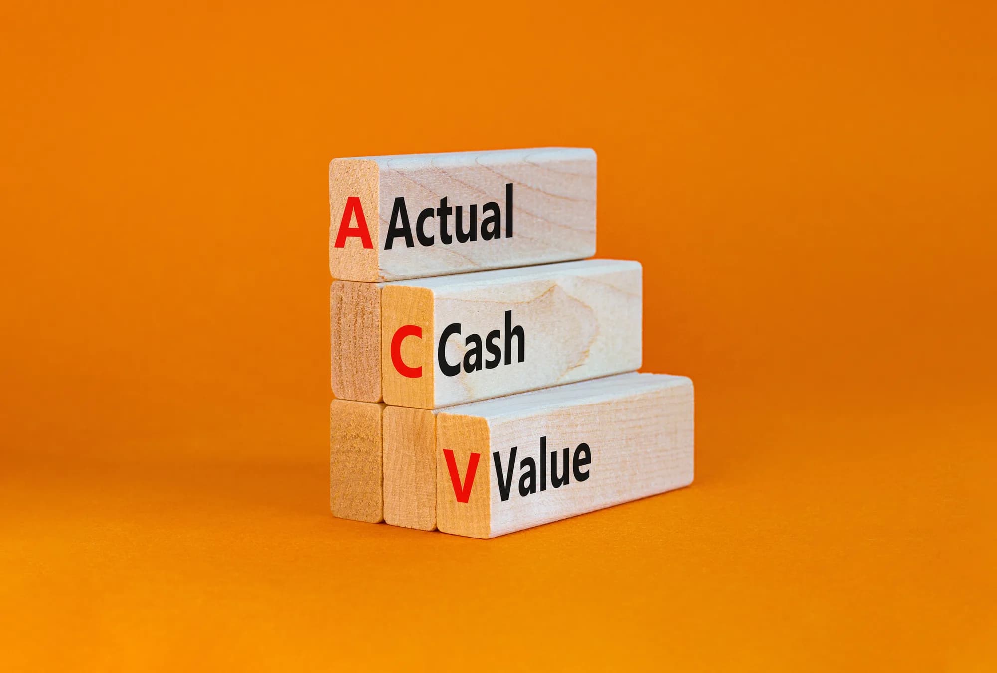 Wooden blocks on an orange background spelling out the words Actual Cash Value.