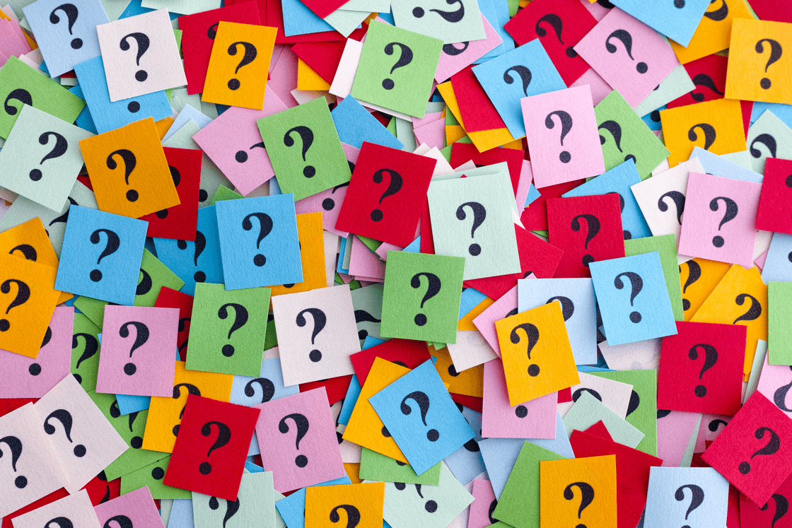 A scattered pile of brightly coloured paper squares, each marked with a question mark.