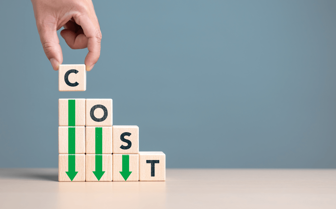A hand stacking wooden blocks that spell COST, with green arrows pointing downward through them.